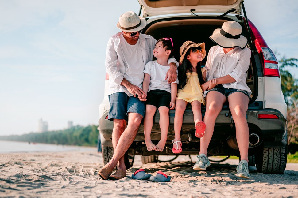 Een gezin van 4 zit in de achterbak van de auto op het strand